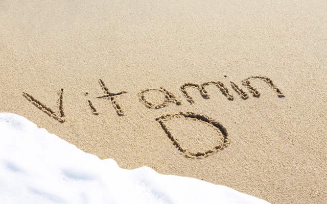 Vitamin D written in the sand with foam from a wave washing up